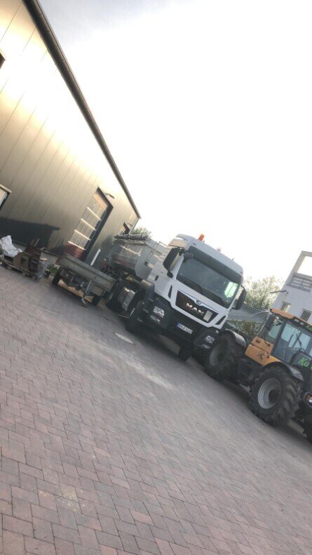Lkw und Radlader vor einer Betriebshalle